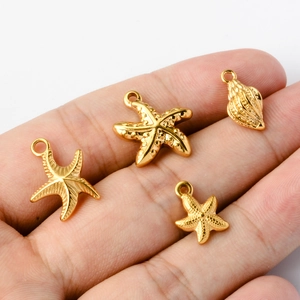 Golden stainless steel starfish and seashell pendants held in hand for DIY jewelry making