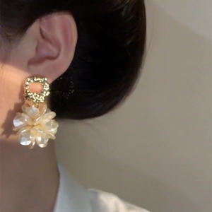 Close-up of gold flower earrings featuring elegant pearl bead clusters on a model