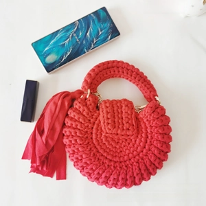 Detail view of red bohemian crochet bag with fringe tassel and thick knit texture