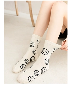 Close-up of cream cotton socks featuring black smiley faces and Have a Nice Day text