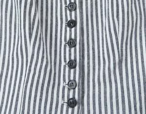 Gros plan sur un tissu à fines rayures noires et blanches avec boutons de la veste