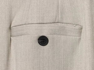 Dettaglio del tessuto in saia grigio chiaro con un bottone nero a quattro fori sui pantaloni