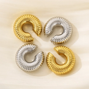 Close-up of gold and silver ribbed C-shaped ear cuffs on soft yellow satin fabric
