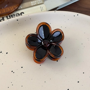 Detailed view of a vintage amber flower claw clip with glossy tortoiseshell finish
