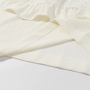 Detailed close-up of white linen-cotton fabric texture and reinforced double-stitched hem