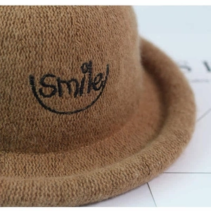 Detail of soft brown wool knit hat with black Smile embroidery and curved brim