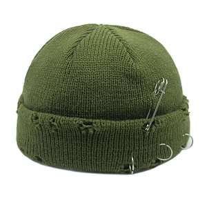 Detail of army green ribbed knit beanie featuring silver safety pin and metal rings