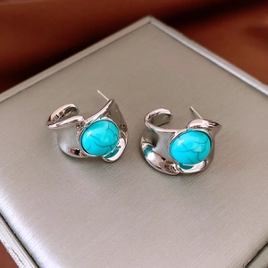 Détail de boucles d'oreilles turquoise rondes sur base argentée et boîte à bijoux grise