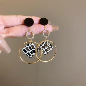 Detail view of gold-plated geometric drop earrings with leopard print and crystals