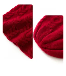 Detailed macro view of red cable knit cashmere hat showing thick texture and pattern