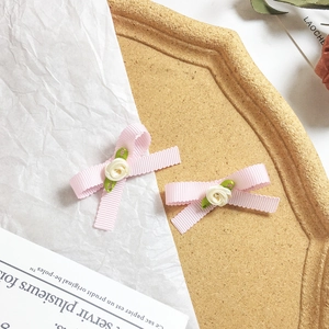 Détail des barrettes à nœud rose avec roses en tissu sur un plateau décoratif élégant