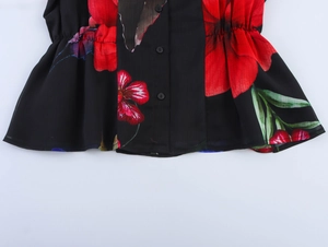 Detail of black floral blouse showing red flower print, round buttons and elastic waist