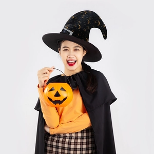 Close-up of a black witch hat with gold stars and an orange pumpkin candy bucket