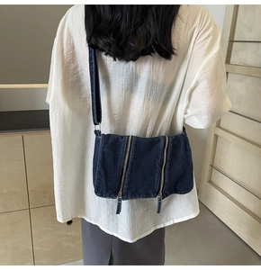 Dunkelblaue Denim-Tragetasche mit Doppelreißverschlüssen, an einem Model präsentiert