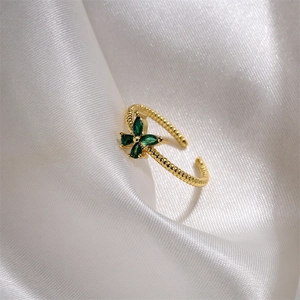 Detail of twisted gold ring featuring a green clover zircon set on white silk fabric