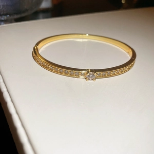 Détail d'un bracelet doré avec cristaux pavés et une pierre centrale ronde sertie