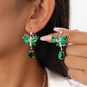 Detail of luxury green butterfly drop earrings with sparkling emerald crystals on model
