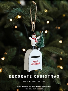 Close-up of a festive red metal mailbox ornament with snowman on a lit Christmas tree