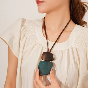 Close-up of a long vintage necklace featuring square turquoise resin and wood pendants