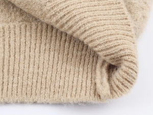 Détail de maille côtelée beige montrant la texture douce du mohair et les fibres de laine
