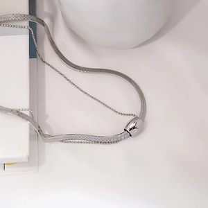 Close-up of silver layered snake chain and bead necklace with cylindrical slider pendant