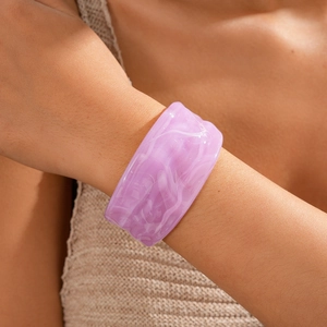 Macro detail of purple marble acrylic cuff bracelet with stylish wavy texture on model wrist