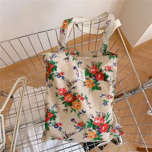 Gros plan du sac fourre-tout en coton à fleurs vintage dans un chariot en métal argenté