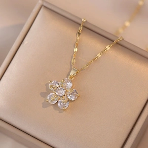 Elegante goldene Blumenhalskette mit Zirkonia auf einer beigen Schmuckschatulle