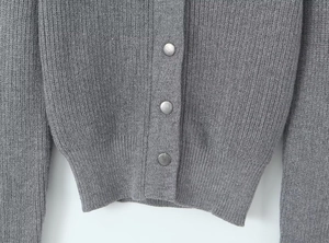 Detail of vertical ribbed knit texture and silver metal buttons on a grey cardigan
