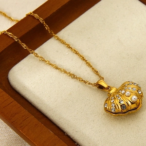 Macro detail of 18K gold shell pendant with zircon and pearl in a velvet jewelry box