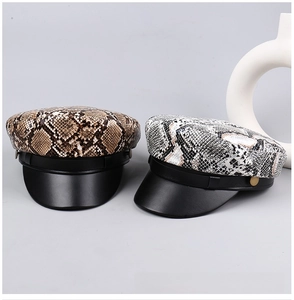 Detailed view of leopard and snake print flat top newsboy caps with black leather brims