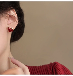 Close-up of 18k gold plated red dragon stud earrings worn by a model in red sweater