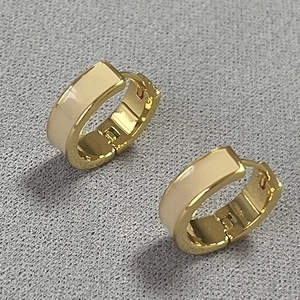 Dettaglio di orecchini a cerchio in ottone vintage con smalto crema e placcatura oro