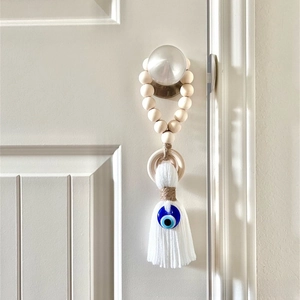 Macro detail of wooden bead ring with white cotton tassel and blue evil eye charm decoration