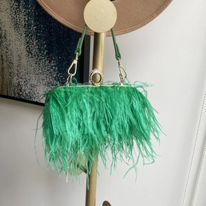Detailed close-up of vibrant emerald green ostrich feathers and rhinestone ring clasp on clutch