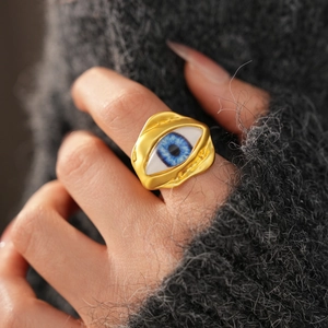 Macro shot of gold evil eye ring with lava texture worn on a grey sweater