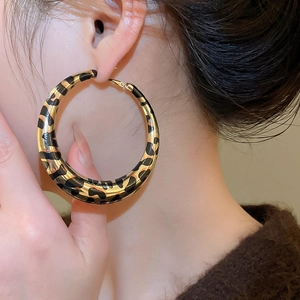 Close-up of a model wearing large golden leopard print hoop earrings for women