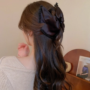 Detailed close-up of large black satin bow hair claw clip with beaded edge detailing