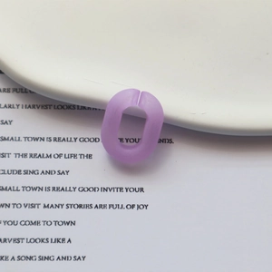 Gros plan d'une bague ovale en résine mate violette sur une assiette blanche avec texte