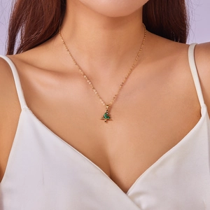 Detail of Christmas tree necklace with green and red enamel worn by a model