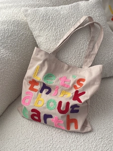 Detail of colorful tufted embroidery Let's think about earth on beige canvas tote bag