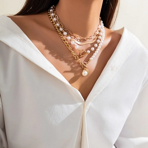 Detail of layered gold alloy necklace with white faux pearls and T-bar closure toggle