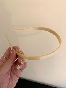 Detail shot of a minimalist beige acrylic leopard print headband held in hand