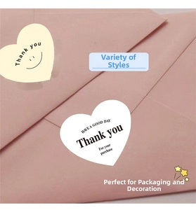 Close-up of heart-shaped Thank You stickers in white and beige on pink envelope