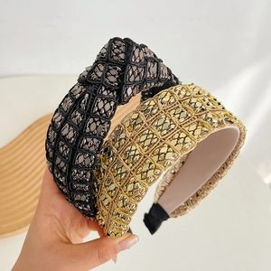 Detail of gold and black knotted headbands with metallic woven texture and high crown design