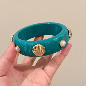 Detail of teal resin bangle with marble texture featuring inlaid shells and pearls