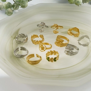 Elegant gold and silver stainless steel leaf rings set on marble tray with nature background