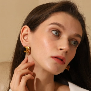 Detailed view of 18K gold plated twisted earrings with pearl on female model ear