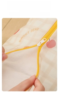 Detail of a plaid laundry bag showing a smooth yellow zipper and sweet bear pattern