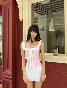 Detail of pink gingham top with white lace ruffle collar and bow tie fastening